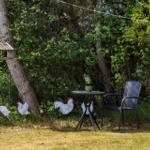 Hinter einem Spielplatz mit Rutsche und Schaukel steht ein Ferienhaus mit Garten.
