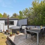 Moderne Ferienhaus mit Balkon, Garten und Hängematten unter Bäumen.