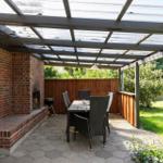 Red garden house with hot tub and umbrella on paved yard.
