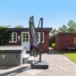 Red wooden shed with white windows and door. Garden with hot tub and umbrella.