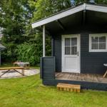 Moderne Holzhütte mit Terrasse, Liege und Sitzgelegenheit im Garten.