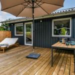 Terrasse mit Sitzgruppe, Sonnenschirm und Blick auf den Garten mit Pavillon.