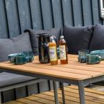 Holztisch mit Getränken und Felldecke im grünen Garten