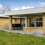 Moderne Ein-Familienhaus mit gelbem Ziegel und grauem Dach, umgeben von Grünfläche.