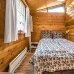 Schlafzimmer mit Holzwand, Bett, Schreibtisch und Kleiderschrank.
