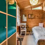 Schlafzimmer mit Holzwänden, Bett und Fenster.