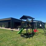 Modernes Haus mit Spielplatz im Freien. Grasfläche und klare Sicht.