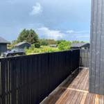 Außenbereich mit Whirlpool, Holzterrasse und schwarzer Holzwand.