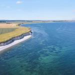 Ländliches Anwesen mit roten Dächern, umgeben von Wäldern und Feldern. Blick auf die Ostsee.