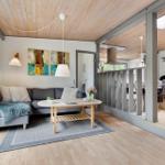 Living room with sofa, table, and balcony view. Kitchen in background.