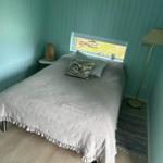 Schlafzimmer mit Bett, Fenster und Stehlampe.