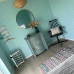 Schlafzimmer mit blauen Wänden, Schrank, Stuhl und Teppich.