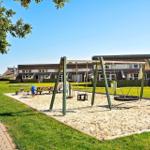 Kinderspielplatz mit Schaukel und Sandkasten vor einem Wohnhaus.