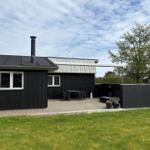 Schwarzes Haus mit Terrasse, Garten und Grillbereich unter freiem Himmel.