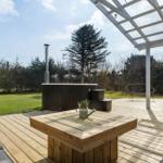 Wooden terrace with hot tub, sun cover, and garden furniture.
