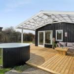 Outdoor area with hot tub, seating group, and wooden deck under a white pergola.
