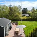 Haus mit Terrasse, Garten und Grillplatz. Umgeben von Bäumen und Hecken.