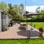 Terrasse mit Tisch, Stühlen und Sonnenschirm neben einem Haus mit Garten.