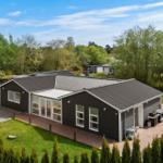 Moderne Villa mit Terrasse, Grill und Garten. Umgeben von Bäumen und Grünflächen.