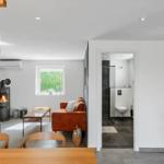 Wohnraum mit Kamin, Sofa und Blick auf Garten. Nebenraum mit Dusche und Toilette.