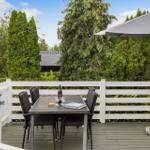 Terrasse mit Pavillon, Tisch und Stühlen. Gelb gestrichene Wand mit Schiebetür und Regal.
