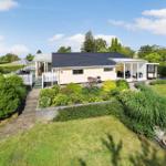 Ein gelbes Ferienhaus mit Terrasse, Sonnenschirm und Gartenzaun.