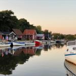 Hafen mit Booten und roten Häusern am Wasser.