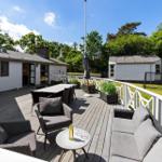 Deck with seating, table, and garden. Background: house and trees.