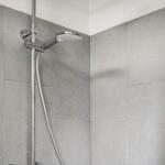 Dusche mit Duschbrause und grauen Fliesen