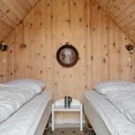 Zwei Betten mit weißen Decken, Holzwände und Decke, kleiner Tisch mit Tasse in der Mitte.