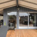 Terrasse mit Grill, Liegestuhl und Schiebetüren zu Wohnbereich.