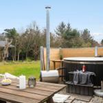 Außenbereich mit Whirlpool, Grill und Tisch. Hintergrund: Holzzaun und Wald.