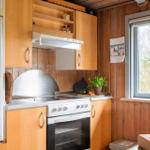 Küche mit Holzschränken, Kühlschrank, Herd und Fenster mit Blick auf Wald.