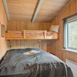 Zimmer mit Doppelbett und erhöhtem Bett, Holzwand und Fenster mit Waldblick.