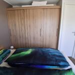 Schlafzimmer mit Bett, Kleiderschrank und Tür