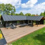 Moderne Villa mit Holzterrasse, Garten und großem Essbereich im Freien.