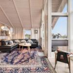 Deck with seating area and dining table. Wooden planks and glass railing. View of residential houses.