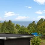 Von der Terrasse bietet sich ein Blick auf das Meer hinter Bäumen.