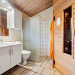 Schlafzimmer mit Holzwand, Bett, Schrank und Fenstern.