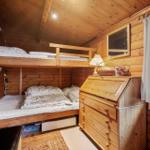 Holzwand mit Spiegel, Schrank und Dekorationen. Fenster und Heizung sichtbar.