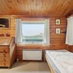 Schlafzimmer mit Holzwand, Bett und Fenster. Decke mit Lampe und Bücherregal.