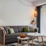 Ein Wohnzimmer mit grauem Sofa, zwei runden Tischen und einer Glastür zum Balkon.