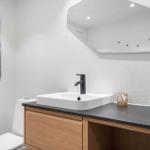 Badezimmer mit Waschbecken, Spiegel und Toilette. Wandbild und Pflanzen auf der Arbeitsplatte.