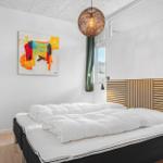 Schlafzimmer mit Bett, Wandbild und Deckenleuchte.