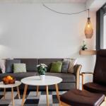 Ein Wohnzimmer mit grauem Sofa, braunem Sessel und runden Tischen.