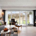 Wohnzimmer mit Sofa, Sitzgruppe und TV. Durchgang zur Terrasse mit Blick auf Grünfläche.