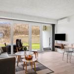 Wohn- und Essbereich mit großem Fenster, Sofa, Tisch und TV.