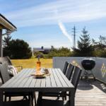 Terrasse mit Tisch, Stühlen und Grill. Blick auf Grasfläche und Bäume.