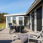 Terrasse mit Tisch, Stühlen und Liegestuhl. Blick auf Garten und Haus.