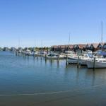 Hafen mit verschiedenen Booten und Stegen unter blauem Himmel.
